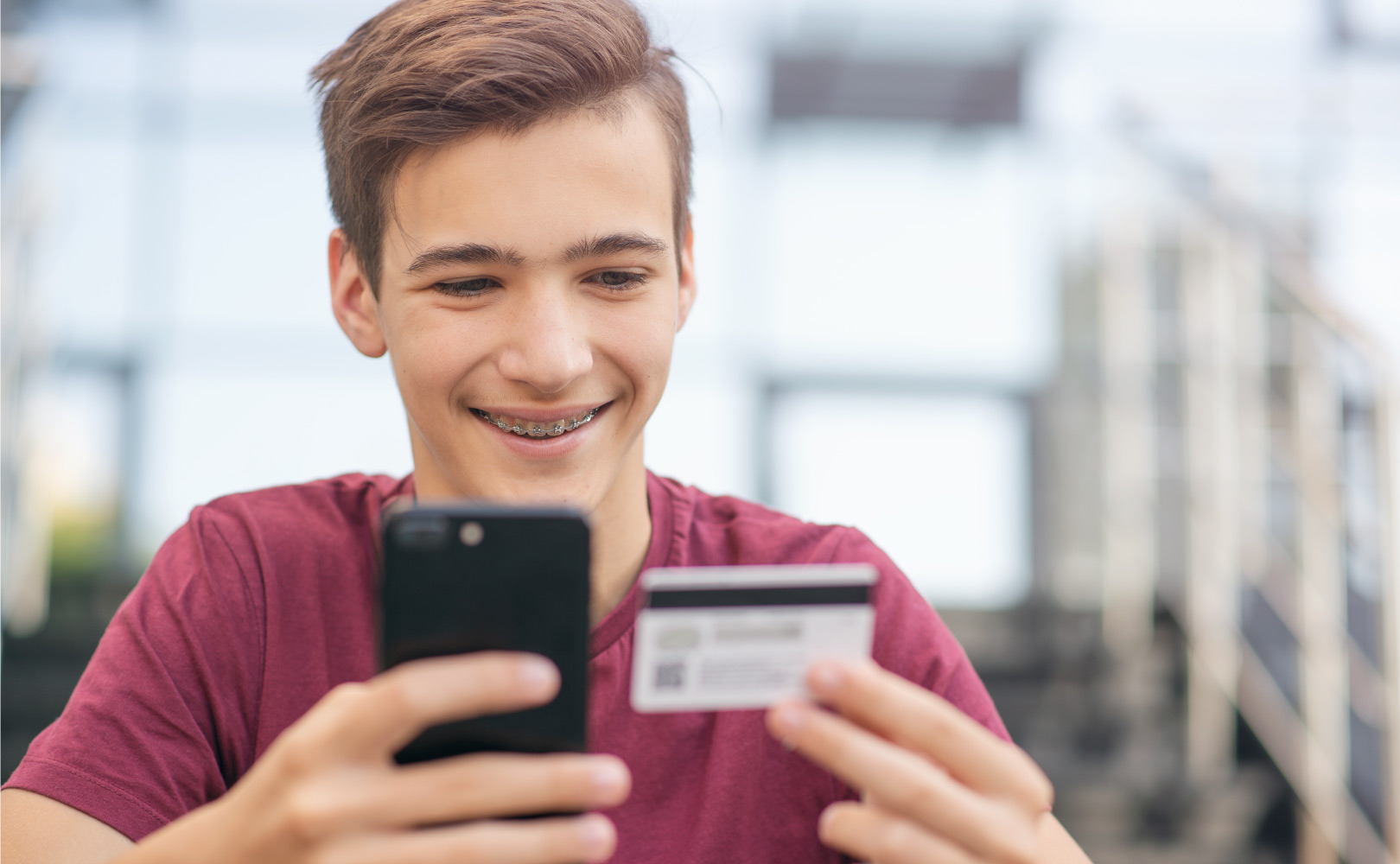 teenage boy using a credit card and phone